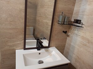 Un baño con lavamanos blanco, un espejo y un inodoro.