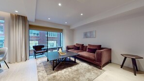 Relax in this stylish living room with a leather sofa, coffee table, and side table, offering a view of the city outside.