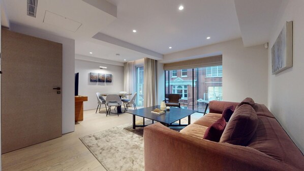 Relax in this inviting living space with a plush sofa, glass coffee table, and large window offering a view of the outside.