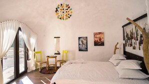 Un dormitorio con una cama, dos sillas, una mesita y una ventana con cortinas.