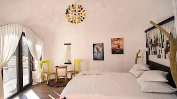 A bedroom with a bed, two chairs, a small table, and a window with curtains.