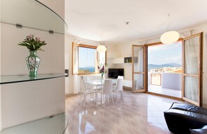 A modern living space with a dining area, a TV, and a view of the city. - Chiara s House in Alghero (Alghero)