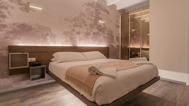 Quarto moderno com uma cama grande, uma mesa de cabeceira e um espelho.