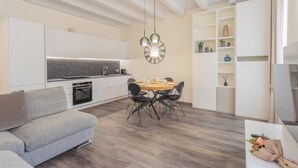 Uma cozinha moderna com forno embutido, uma mesa de jantar com cadeiras e um relógio fixado na parede.