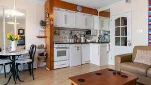 Ett kompakt bostadsutrymme med ett litet kök, en matplats och en soffa.