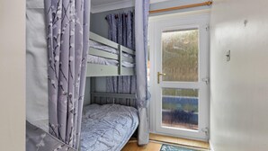 Ett rum med en våningssäng, en dörr med ett frostat glasparti och en dörrmatta med ett landskapsmotiv.
