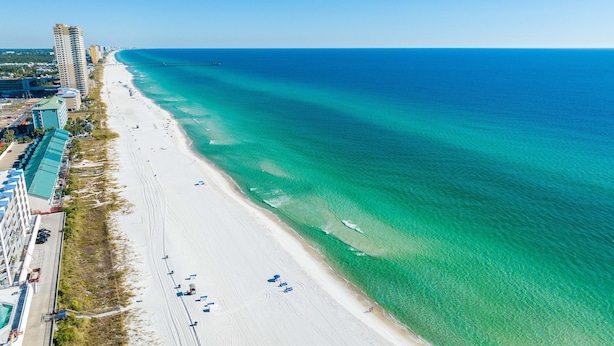 An aerial view of a beach with clear turquoise waters, a long stretch of sandy beach, and high-rise buildings along the coastline. - The Caribbean Queen Beach House. Beach☆Pools☆Art☆Sleeps 8☆1,000 sq ft. (Panama City)