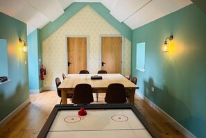 A room with a wooden table, chairs, a shuffleboard table, and two doors. - Beautiful Peak District country cottage sleeping three people - dog-friendly (Buxton)