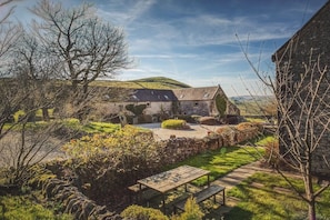 A stone building with a garden in front, a bench, and a pathway leading to a hill. - Beautiful Peak District country cottage sleeping three people - dog-friendly (Buxton)