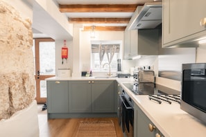 A modern kitchen with grey cabinets, a built-in oven, and a stainless steel range hood. - Luxury cottage for three people in the Peak District National Park (Buxton)