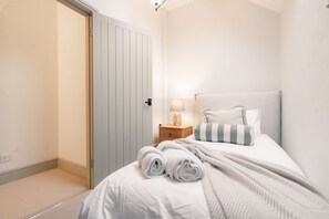 A bedroom with a bed, a nightstand, a lamp, and a door. - Luxury cottage for three people in the Peak District National Park (Buxton)