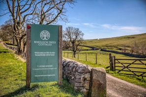 A sign for Wheeldon Trees Cottages with contact information and a welcoming message. - Luxury cottage for three people in the Peak District National Park (Buxton)