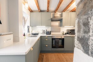 Una cocina moderna con gabinetes grises, una campana extractora de acero inoxidable y un horno empotrado.