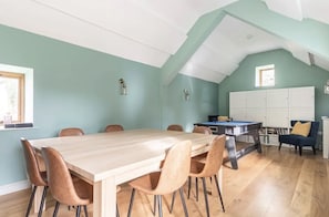 Ein Essbereich mit Holztisch und Stühlen, einem Billardtisch und einer Küchenzeile mit Schränken.
