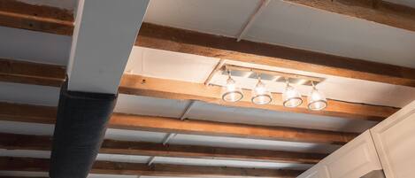 A room with exposed wooden beams, a ceiling light fixture, and a window.