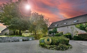 A stone building with a gravel driveway, a large tree, and a well-maintained garden with a decorative stone feature. - Country cottage for four people set in 12 acres of Peak District National Park (Buxton)