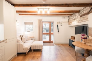 A cozy room with a wooden floor, a sofa, a small table, and a stone wall.