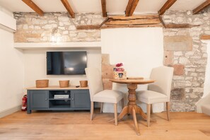 Ein gemütliches Zimmer mit Steinsandsteinwand, einem Flachbildfernseher, einem kleinen Tisch mit Stühlen und einem blauen Schrank.
