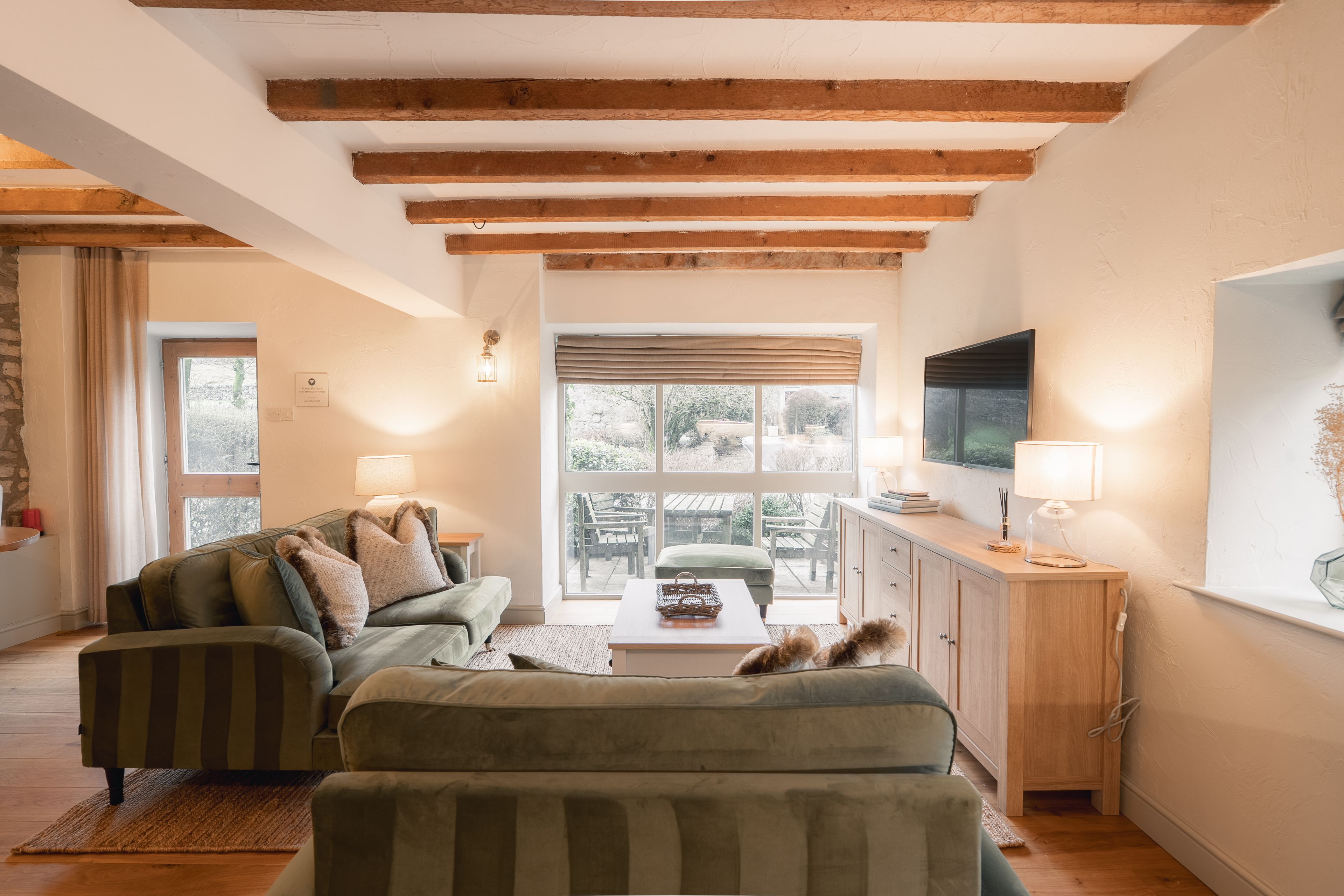 A cozy living room with a sofa, a coffee table, and a TV on a wooden cabinet.