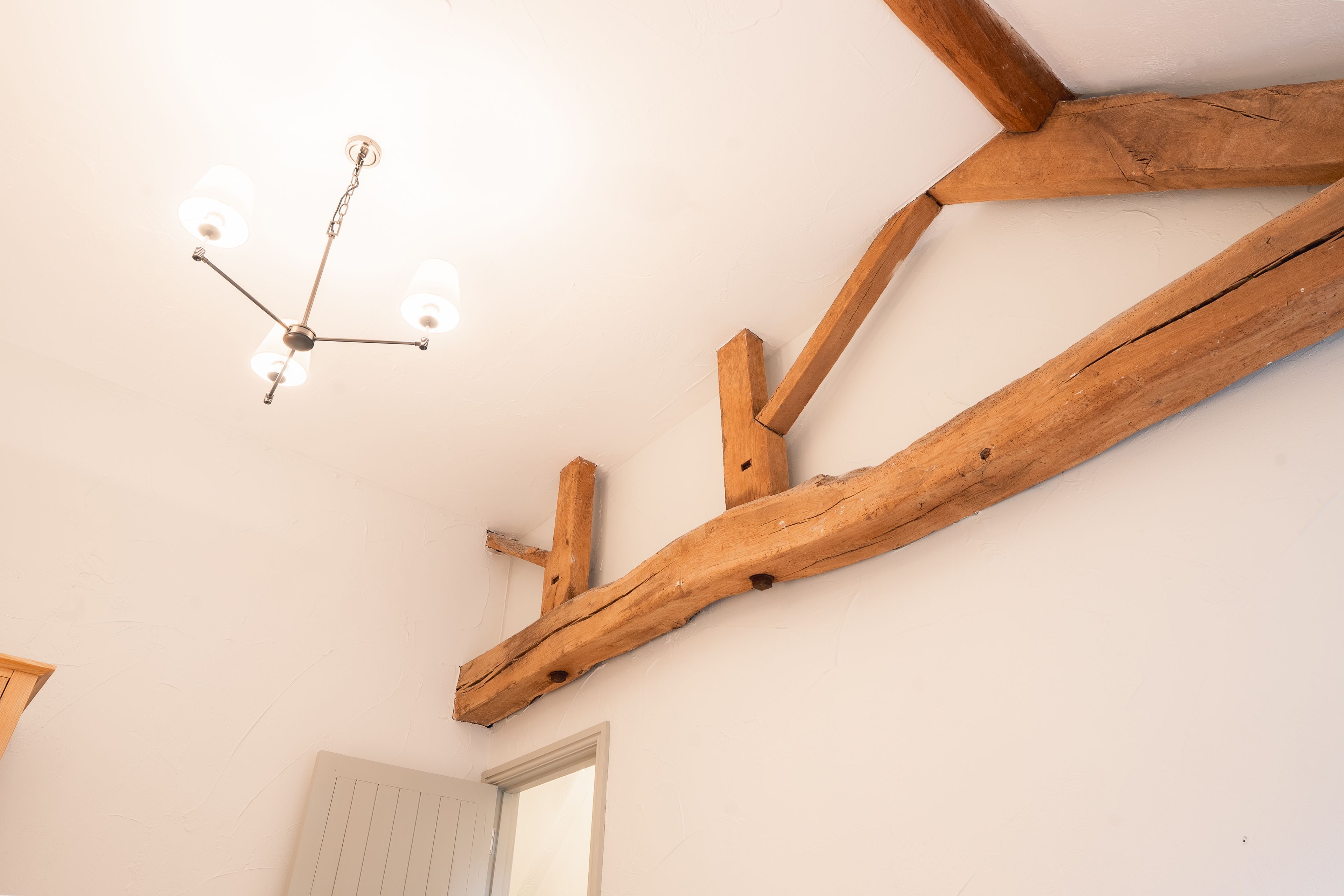 Eine Decke mit freiliegenden Holzbalken und einer hängenden Leuchte.