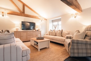 A modern living room with a television, sofa, and armchair. - Luxury accessible cottage with two double bedrooms in the Peak District Park (Buxton)