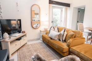 A living room with a sofa, TV, and a mirror with lights.