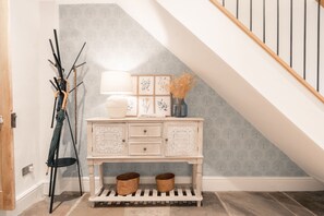 Una escalera con barandilla de madera y pared blanca con diseño de hojas.
