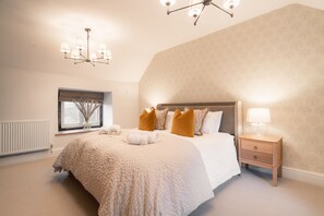 A bedroom with a large bed, a nightstand, a window with a view, and a ceiling light fixture.