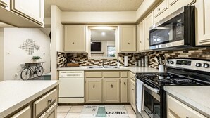 Una cocina con armarios color beige, un microondas, una estufa y un lavavajillas.