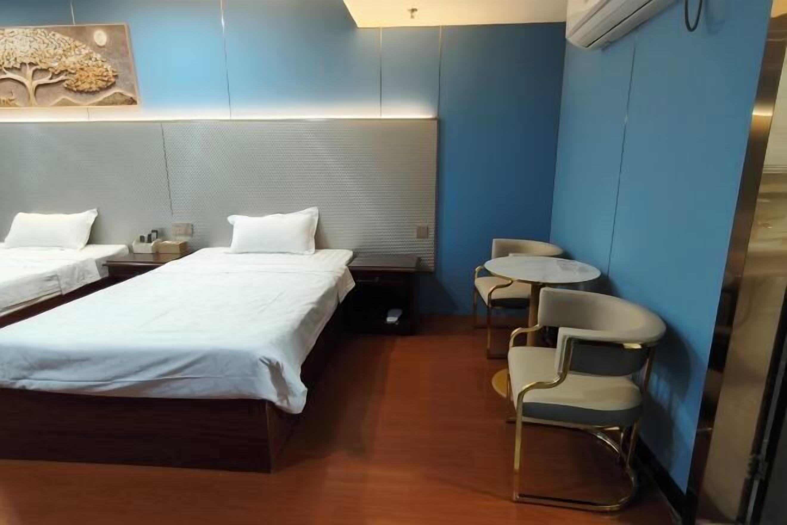 Ett hotellrum med två sängar, ett litet runt bord och två stolar.