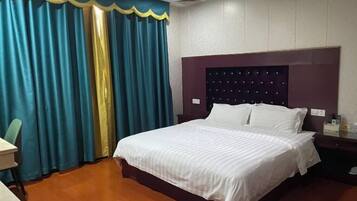 A hotel room with a large bed, a nightstand, a desk, and a chair.