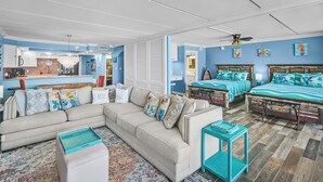 A living room with a sofa, two beds, a coffee table, and a small table.