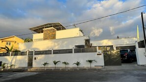 A modern building with a flat roof, a gated entrance, and a parking area. - Private Spacious villa  Ocean view and Rooftop Bar. Tourism Authority licence. (Flic en Flac)