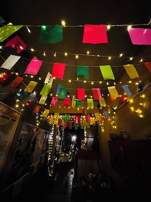 A room with a ceiling decorated with colorful paper flags and string lights. - Casa de huespedes La Casa Bonita (La Paz)