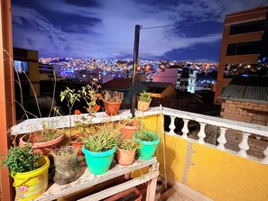 A balcony with potted plants and a view of a cityscape at night. - Casa de huespedes La Casa Bonita (La Paz)