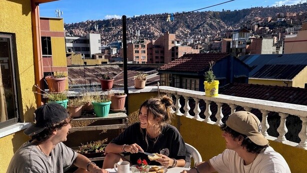 A group of people dining on a balcony with a cityscape view. - Casa de huespedes La Casa Bonita (La Paz)