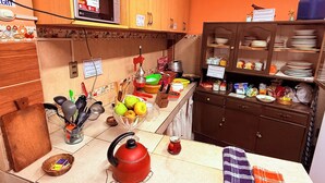 A kitchen with a microwave, kettle, and various kitchen utensils on the counter. - Casa de huespedes La Casa Bonita (La Paz)