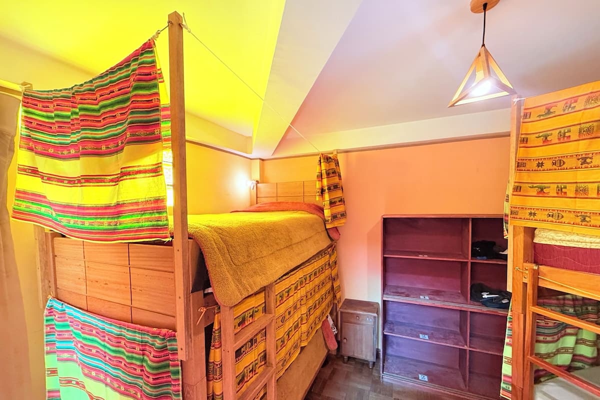 Ein Zimmer mit Etagenbett, kleinem Regal und einer Pendelleuchte.