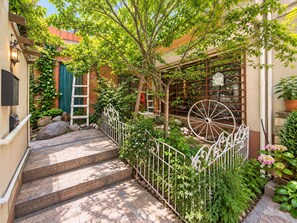 A courtyard with a metal fence, steps leading to a building, and a large wooden wheel. - Casa de huespedes La Casa Bonita (La Paz)