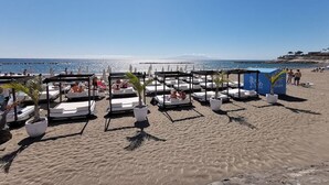 Une plage avec des transats, des parasols et des plantes en pot.