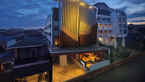 A modern hotel with a unique architectural design, featuring a prominent vertical structure and a well-lit outdoor area.