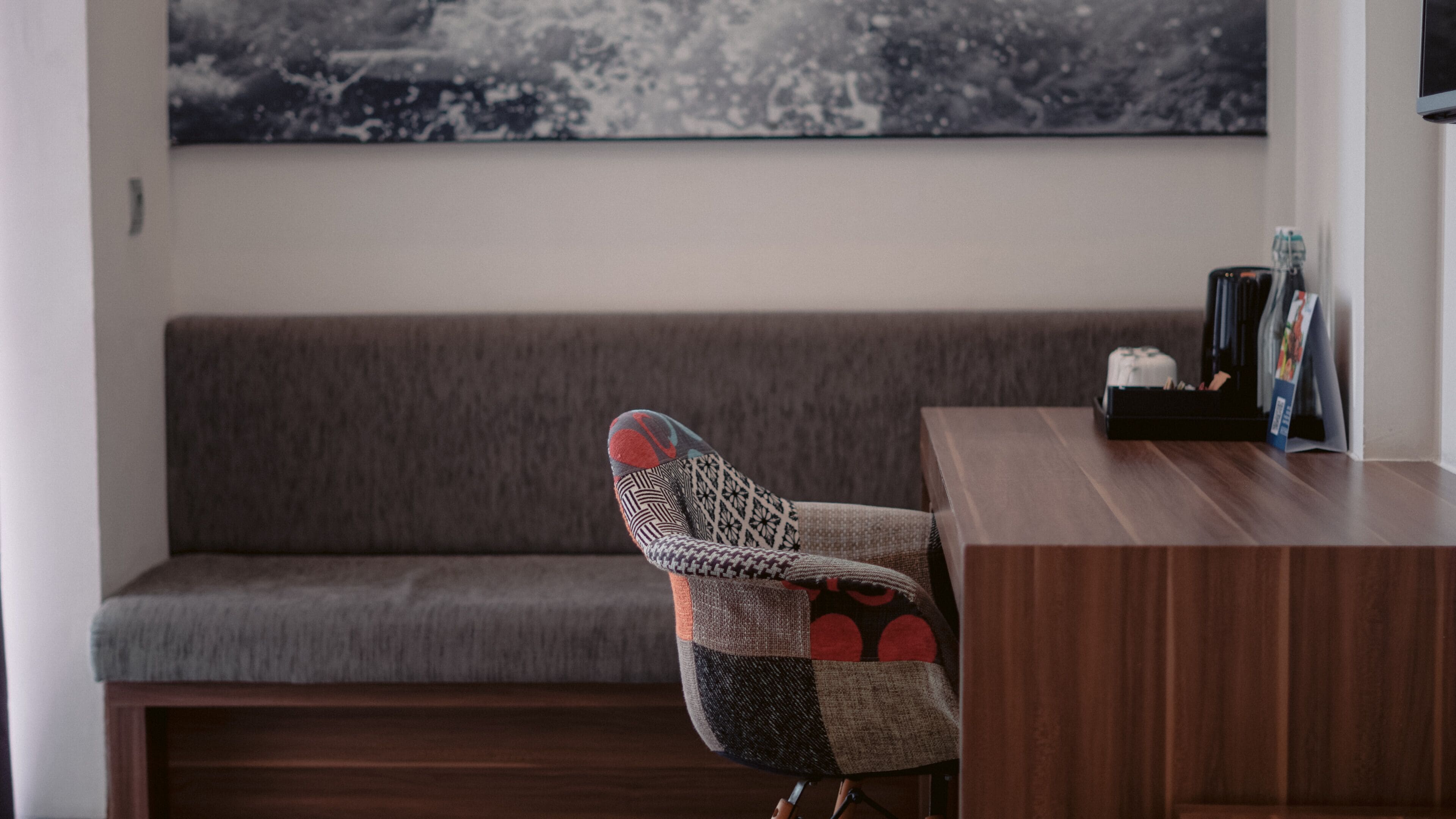 Ein modernes Wohnzimmer mit einem grauen Sofa, einem Holztisch und einem gemusterten Sessel.