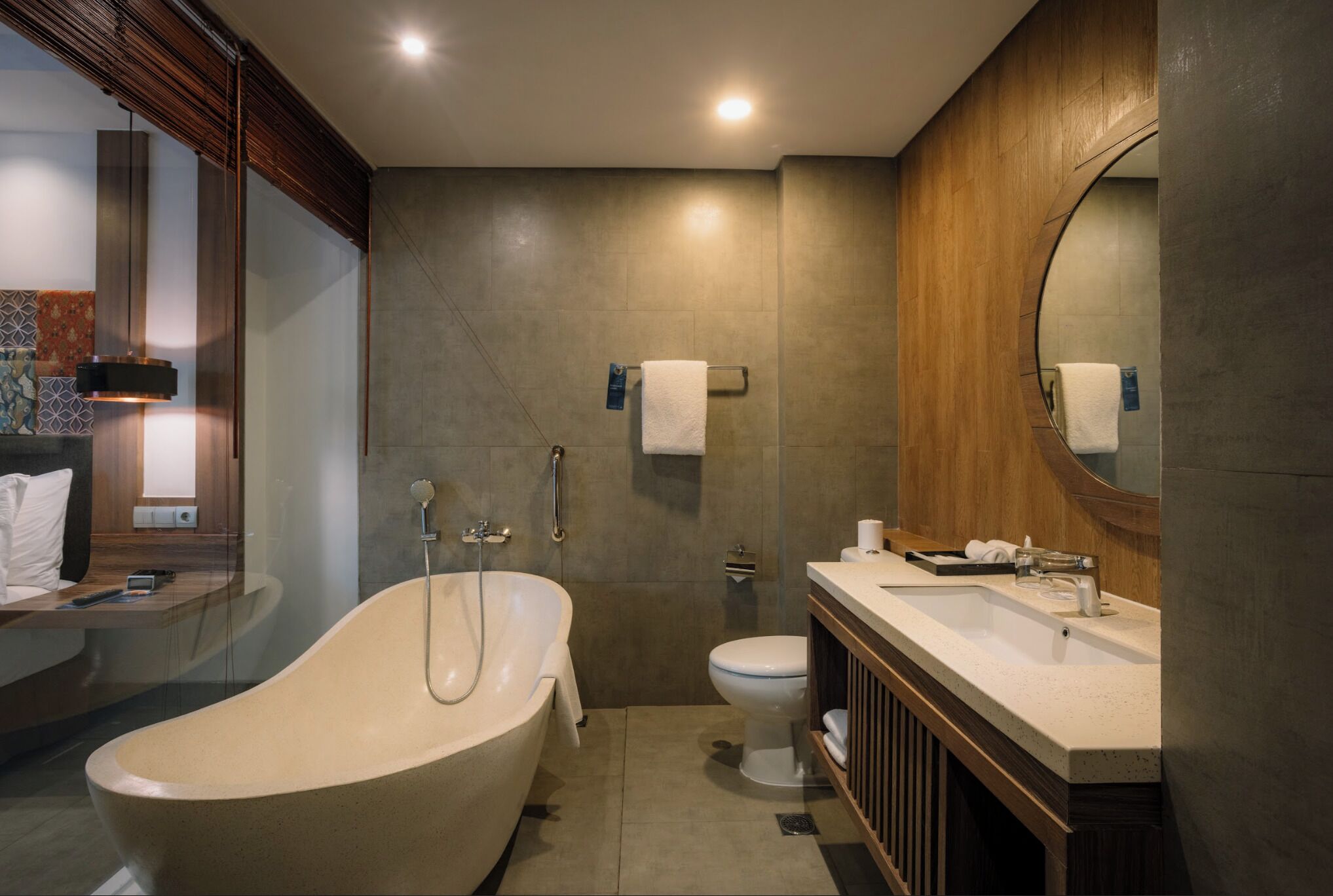 A modern bathroom with a freestanding bathtub, a toilet, and a vanity with a mirror.