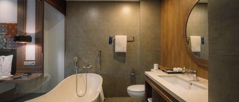 A modern bathroom with a freestanding bathtub, a toilet, and a vanity with a mirror.