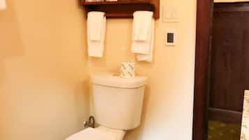 A bathroom with a toilet, a shelf with towels, and a wooden door frame.