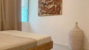 A bedroom with a bed, a large painting on the wall, and a woven basket on the floor. - La Casa Verde x Townhouse in Mermoz, Dakar (Dakar)