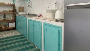 A kitchen with teal cabinets, a white tiled backsplash, a blender, and a refrigerator. - La Casa Verde x Townhouse in Mermoz, Dakar (Dakar)