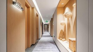 Un pasillo de hotel con paredes de madera, suelo de mármol y una recepción decorada con objetos ornamentales.
