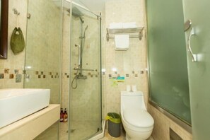 A bathroom with a glass-enclosed shower, a white sink, and a toilet.