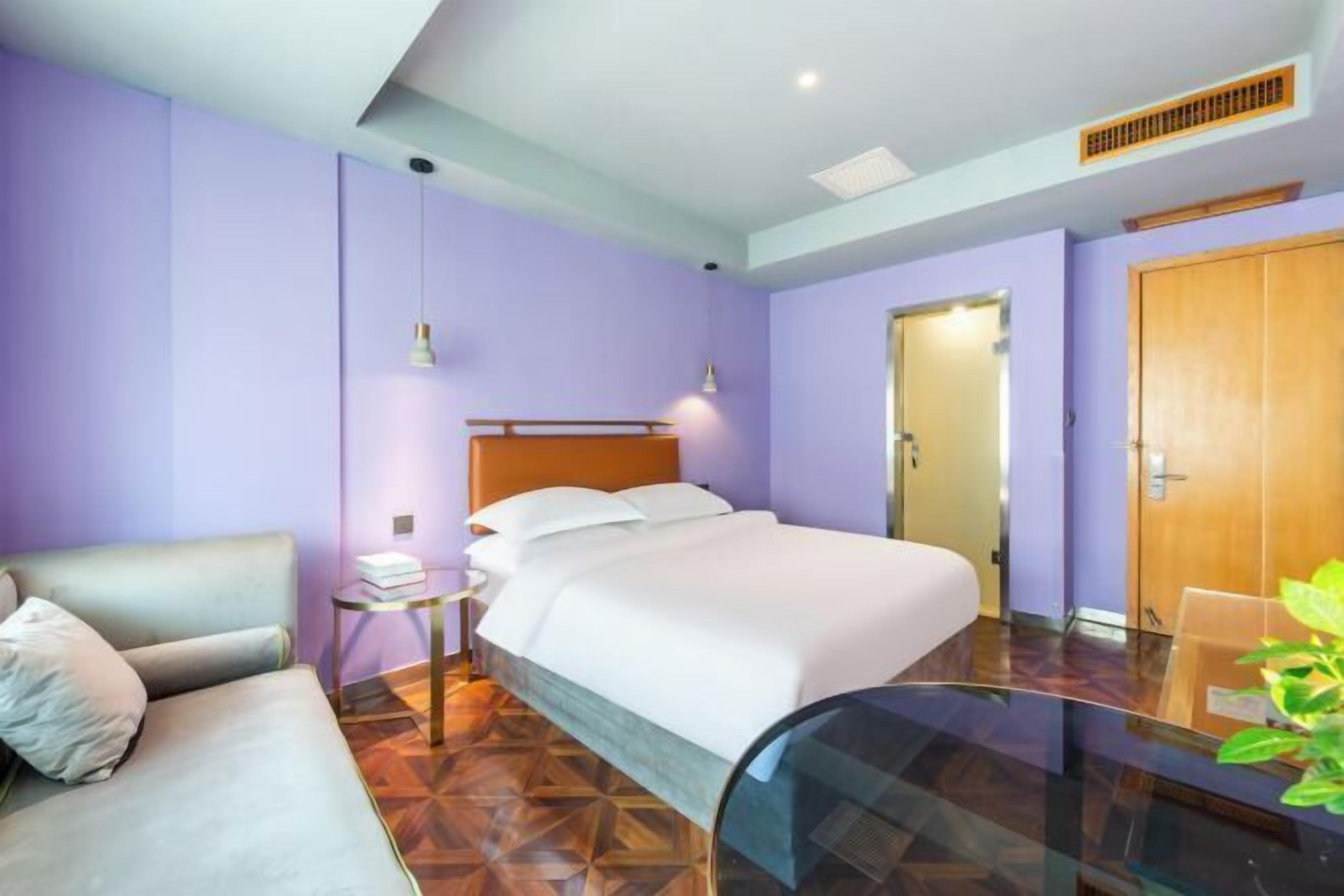 A hotel room with a bed, a small table, a chair, and a sofa.